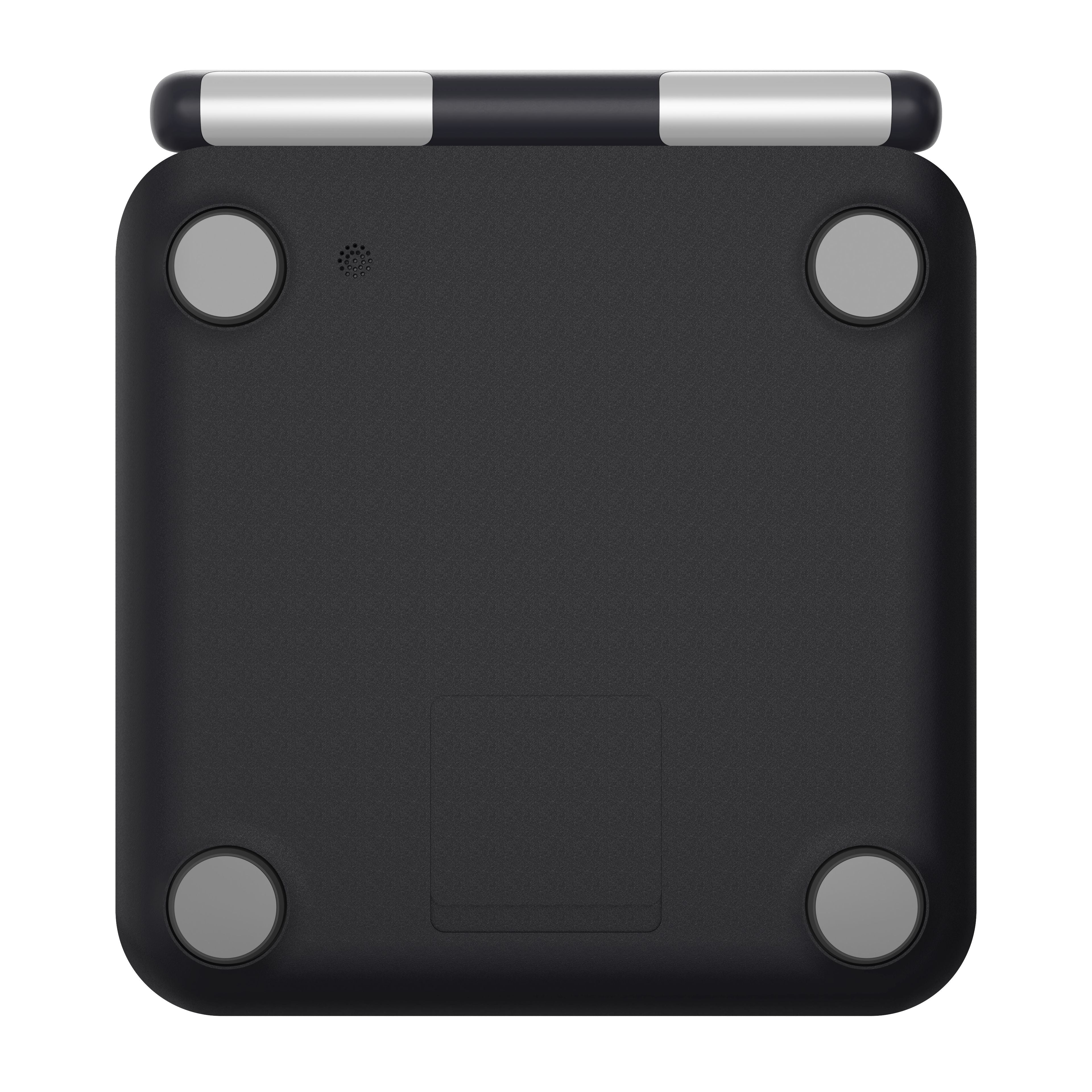 The bottom view of a digital scale showing its matte black textured body, four gray circular feet, and a silver and black hinge mechanism at the top, isolated on a white background.